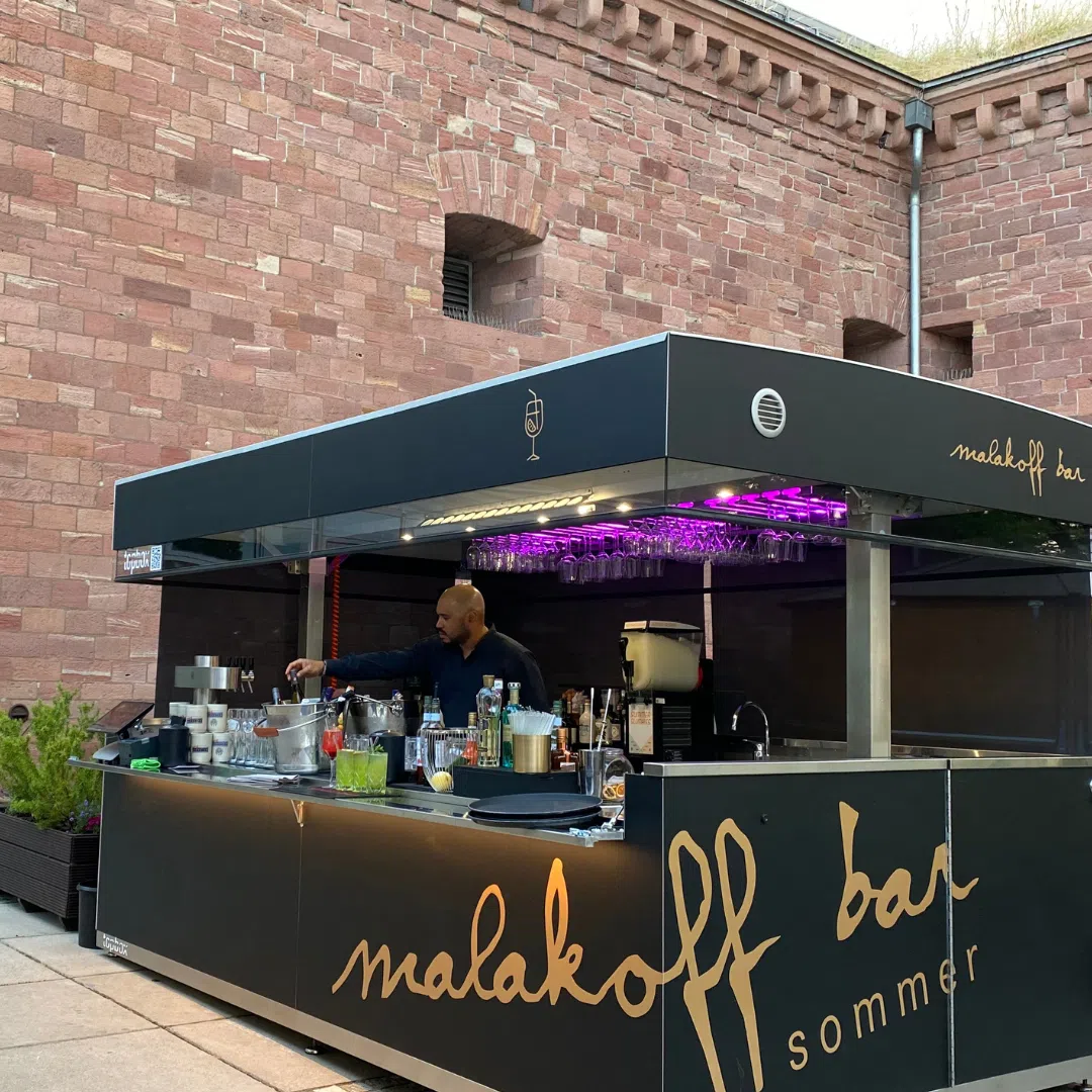 Outdoor mobile bar and kitchen with people enjoying drinks